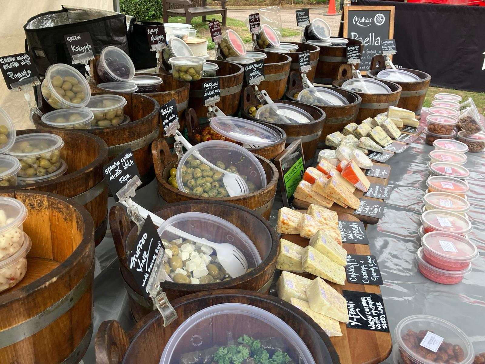 Dave's Olives stall with labelled olive barrels and cheeses