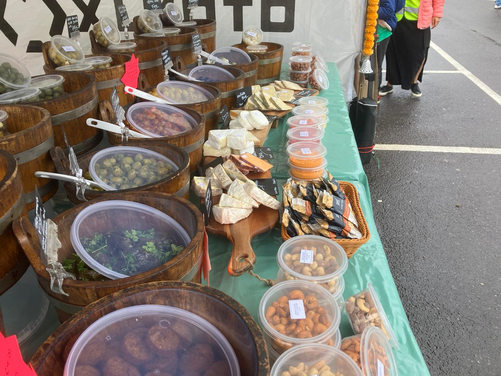Market stall from elevated angle showing olive barrels and produce