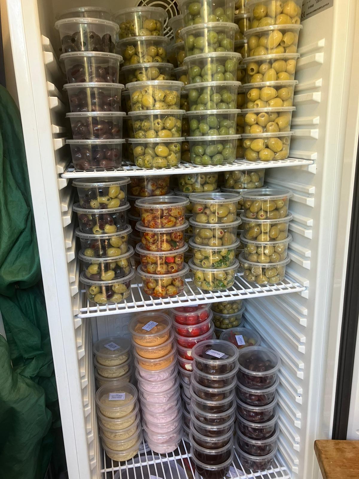 Fridge stocked with packaged olive tubs and dips for wholesale
